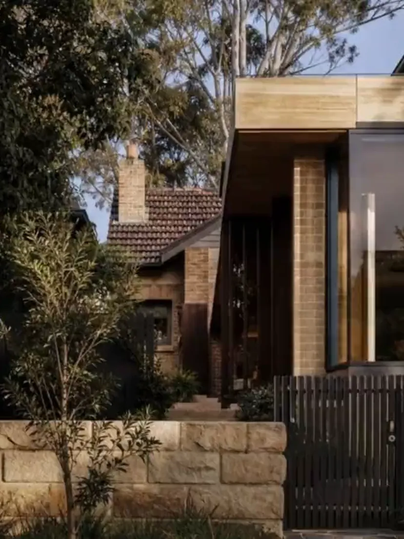 Concept visualisation — a finished brick home behind a sandstone wall at twilight
