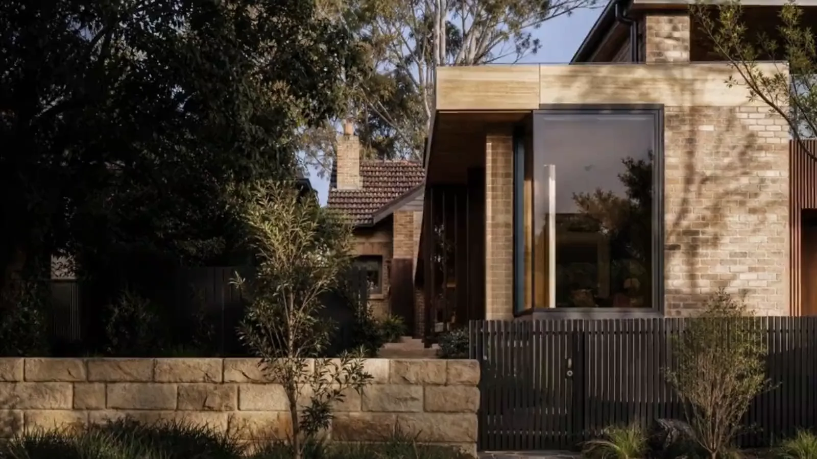 Concept visualisation — a finished brick home behind a sandstone wall at twilight