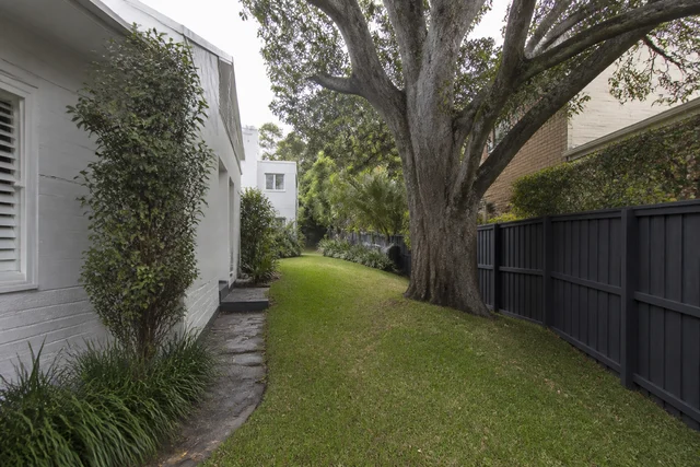 Sloping residential site with mature trees and an existing brick home
