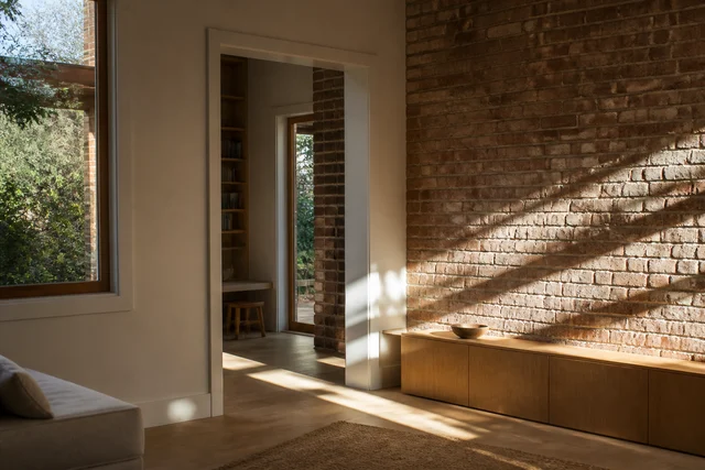 Soft daylight moving across textured walls and timber joinery inside a home